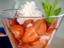 Boozy strawberries with coconut are garnished with a sprig of mint.