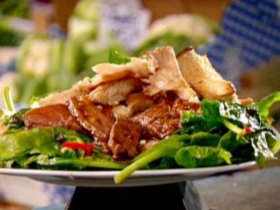 Thinly sliced beef fillet in oyster sauce is placed on top of a plate of greens.