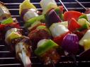 Pieces of lamb neck fillets are placed on a skewer with red and green peppers, bananas, red onions, and pineapple.
