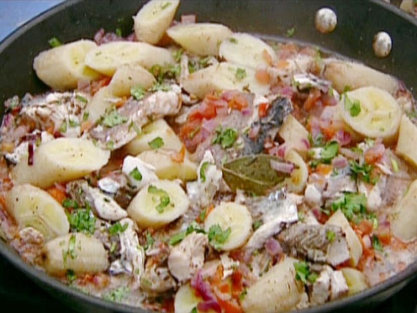 Spicy mackerel with green bananas is cooked in a skillet with tomatoes, red onion, garlic, and several spices including pepper and allspice.