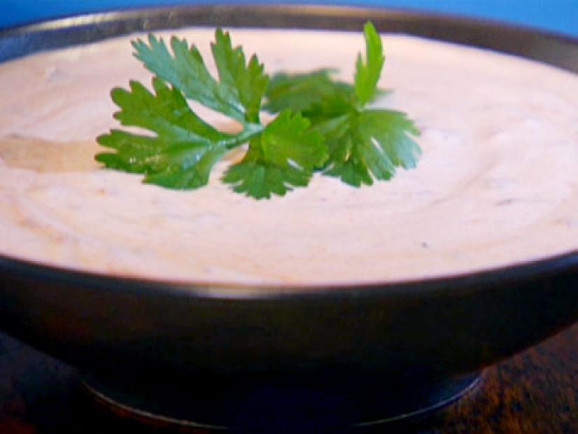 A bowl of chipotle sour cream garnished with herb.