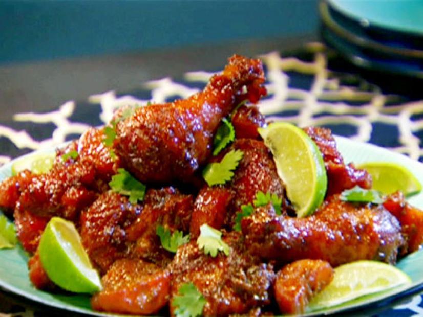 Trinidadian style chicken is garnished with cilantro and lime wedges.