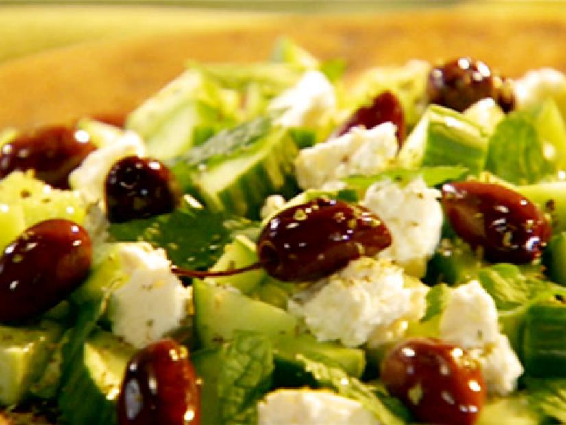 Cucumber feta salad with mint leaves and dried oregano is topped with kalamata olives.