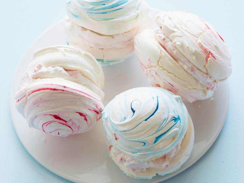 Pink meringues with raspberry cream are served with fresh raspberries.