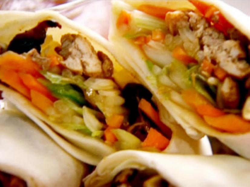 Chicken and vegetable spring rolls cut diagonally are filled with chicken, carrots, spring onions, and bean sprouts. 