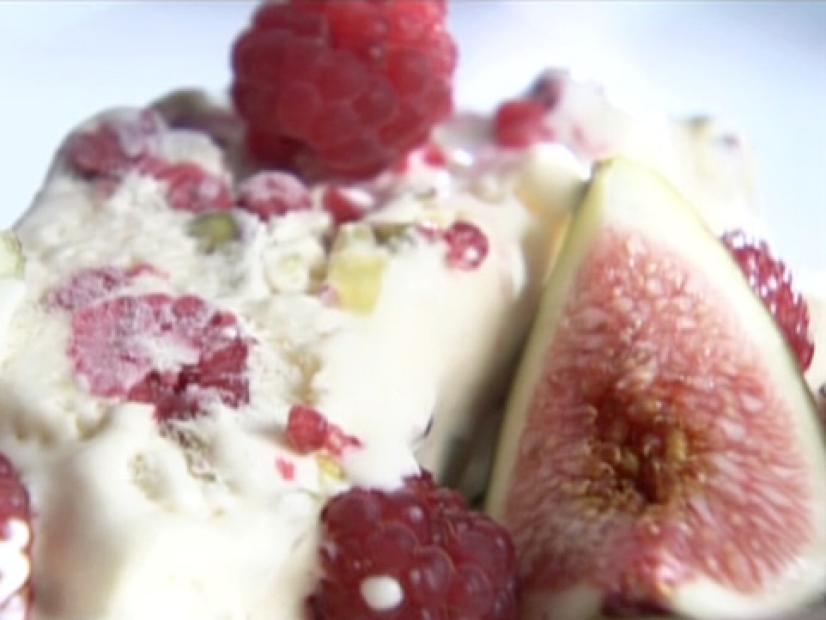 A semifreddo with pistachio nuts is topped with fresh raspberries.