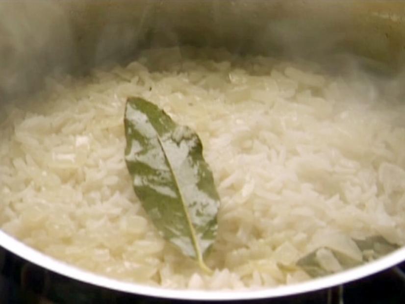 Pilaf cooks in a pot with white wine and bay leaves.