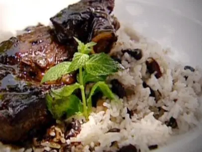 Lamb is served on a bed of rice and peas which is made with rice and black beans.