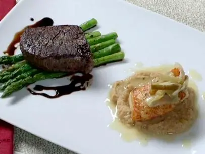 Pan roasted filet mignon atop asparagus is served with sea bass on a bed of roasted cauliflower puree.