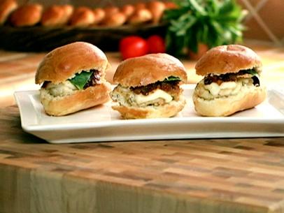 A platter with three Italian chicken sliders with tomato jam, sliced mozarella cheese, and fresh basil.