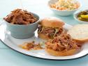 Pulled pork on two sandwiches and in a small pale blue dish that is placed on an oval plate