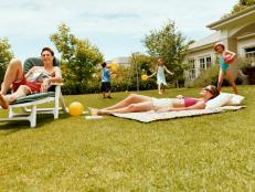 Three Children Play With Balls in a Garden While Their Parents are Sunbathing