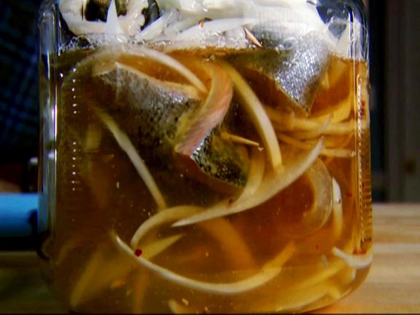 A jar containing brine made of trout, onions, red pepper flakes and other ingredients